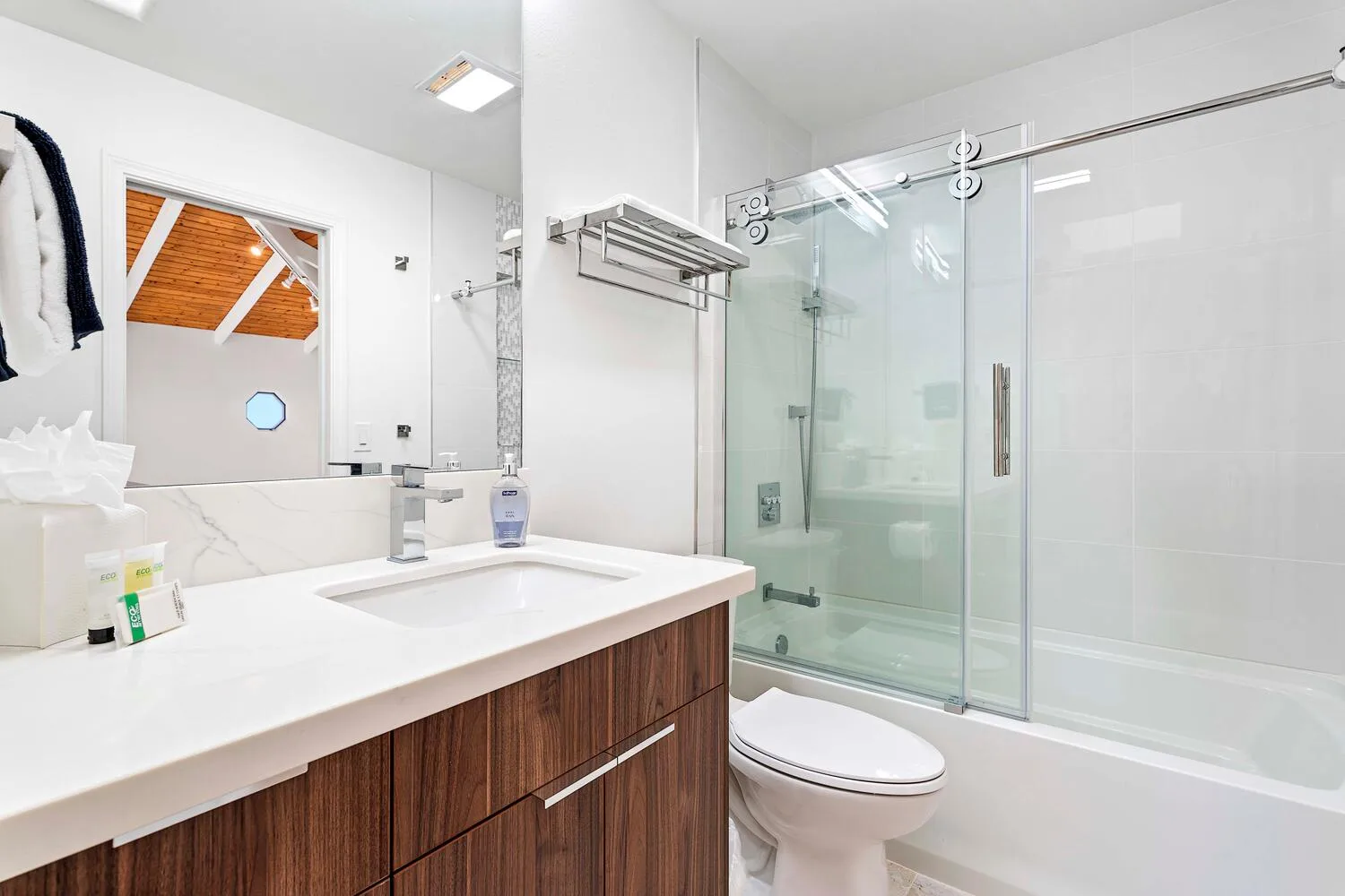 A bathroom with a wide sink counter and a glass shower.