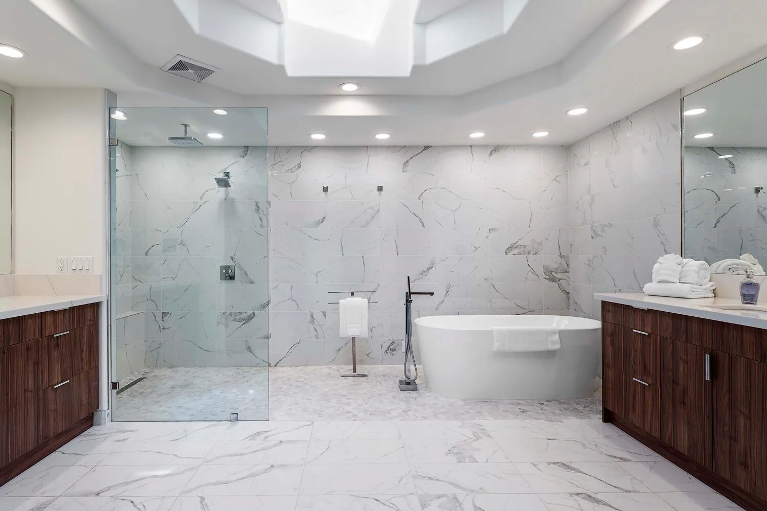 A spacious marble bathroom features a glass shower and a freestanding bathtub.