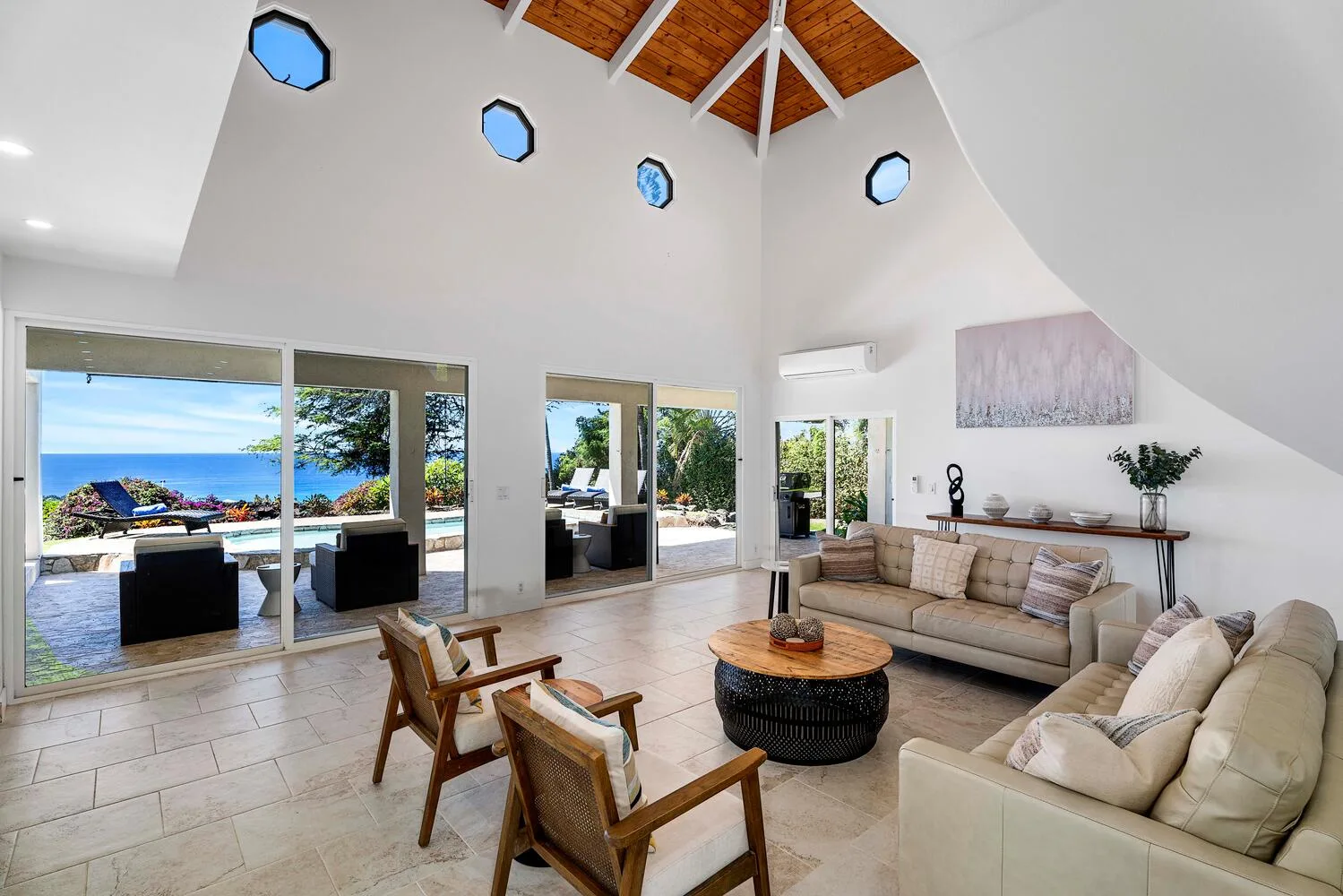 A bright living room with seating, large windows, and an ocean view.