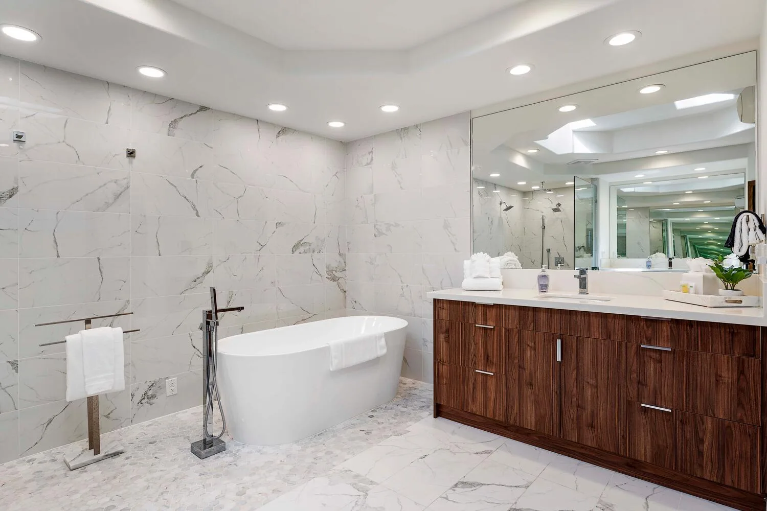 A bright bathroom with a freestanding bathtub and a wide vanity beneath a mirror.