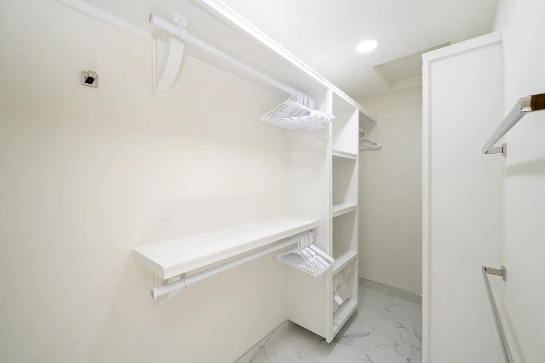 A bright walk-in closet with built-in shelving and hanging rails.