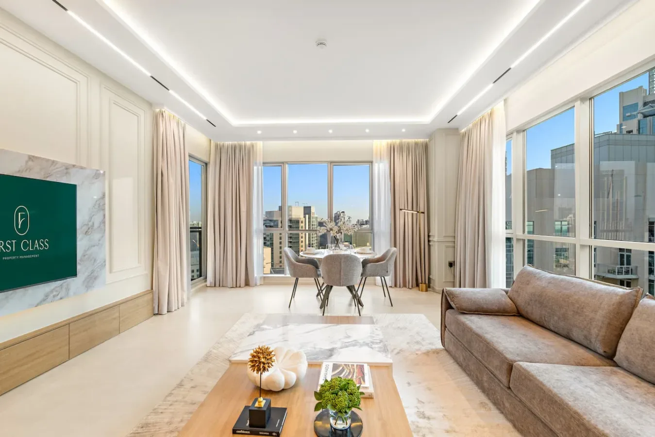 Sala luminosa con asientos, un comedor y grandes ventanas con vistas a la ciudad.