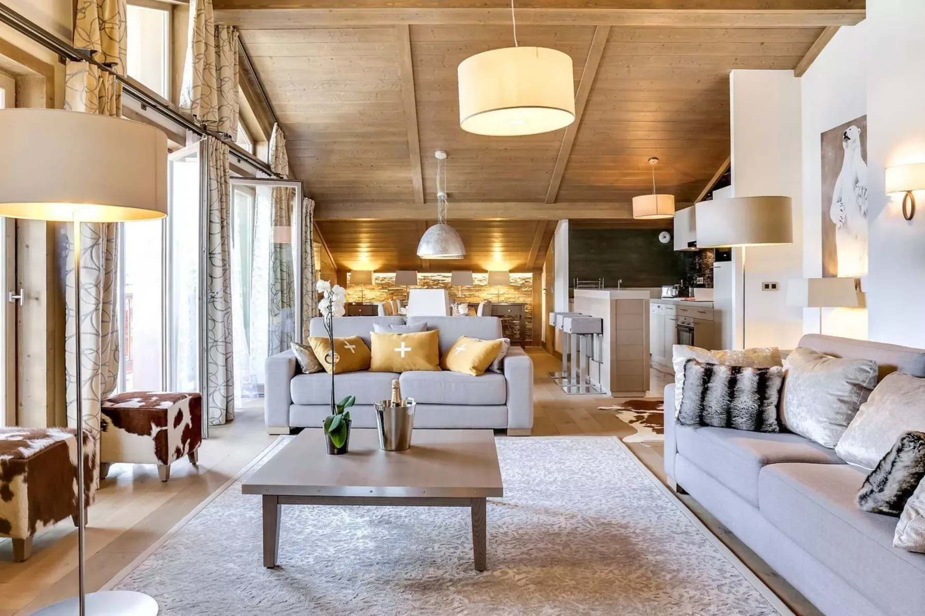 A bright living room with seating around a coffee table and an open kitchen beyond.