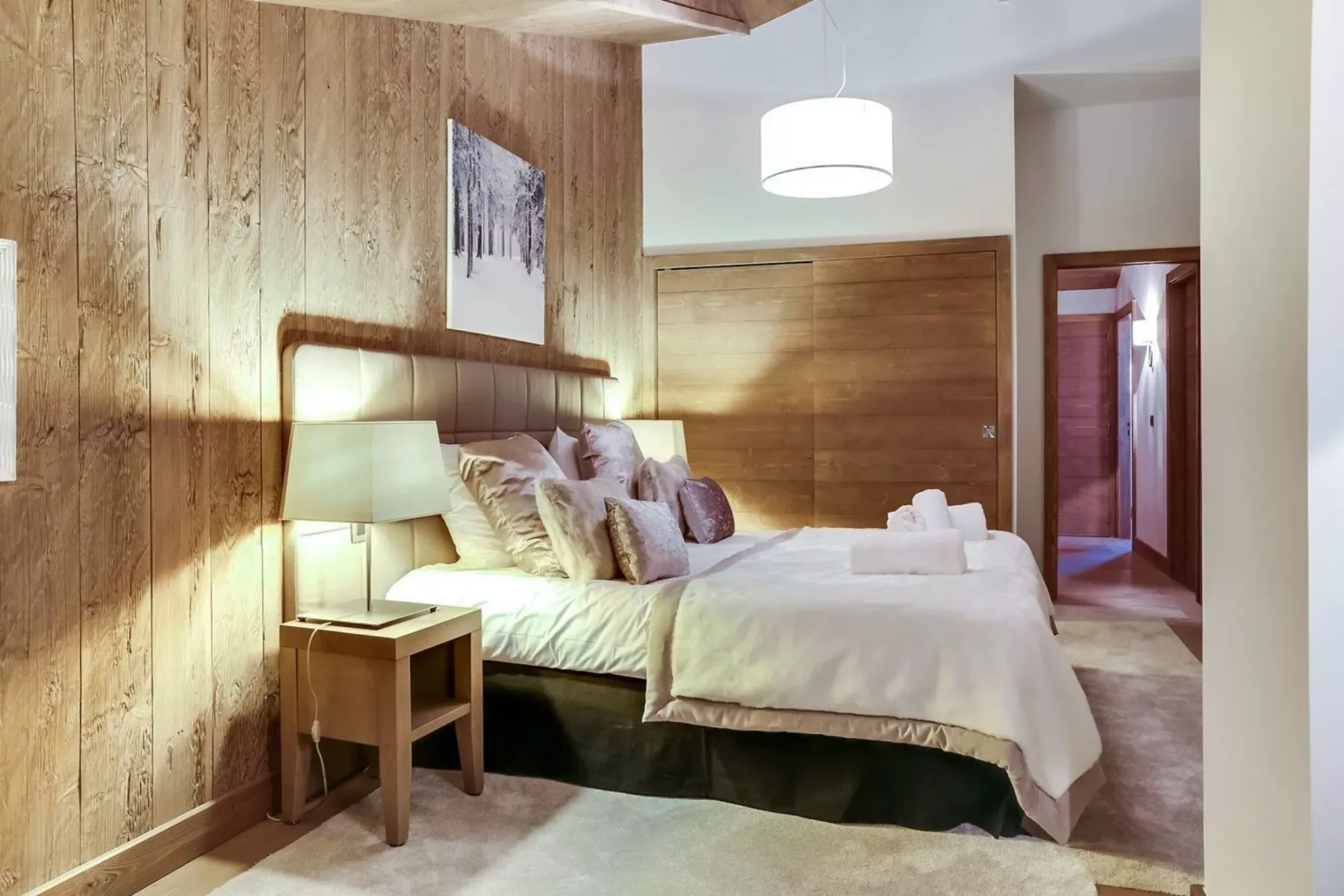 A bedroom with a bed, bedside table, and wood-paneled walls.