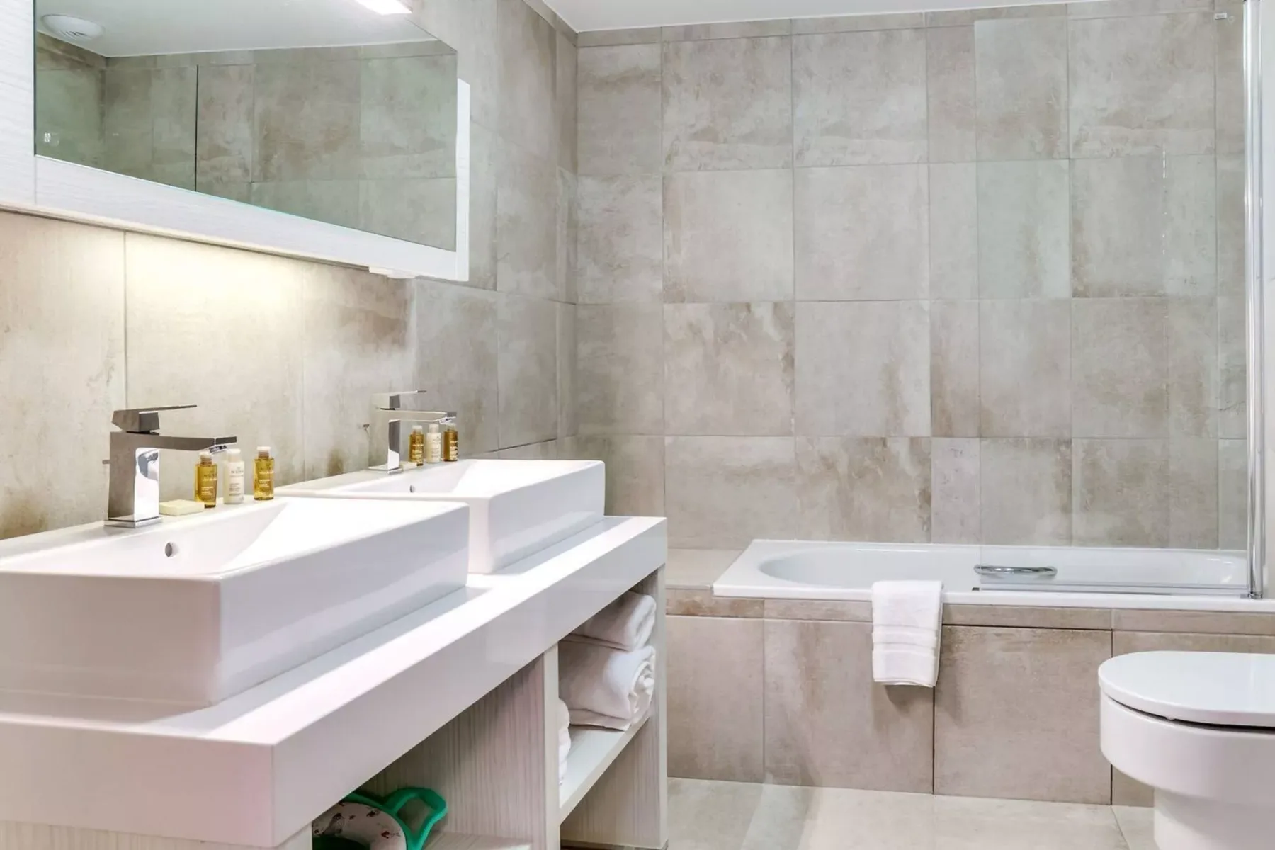 A tiled bathroom with a bathtub, sink, and mirror.