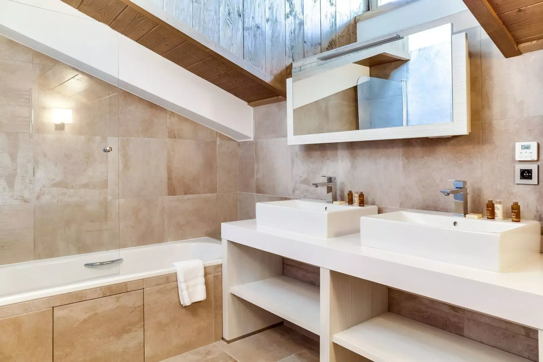 A bathroom with a bathtub, two sinks, and a large wall mirror.