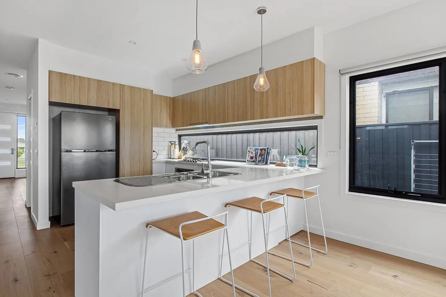 Una cocina moderna tiene una isla central con asientos de barra y gabinetes de madera.