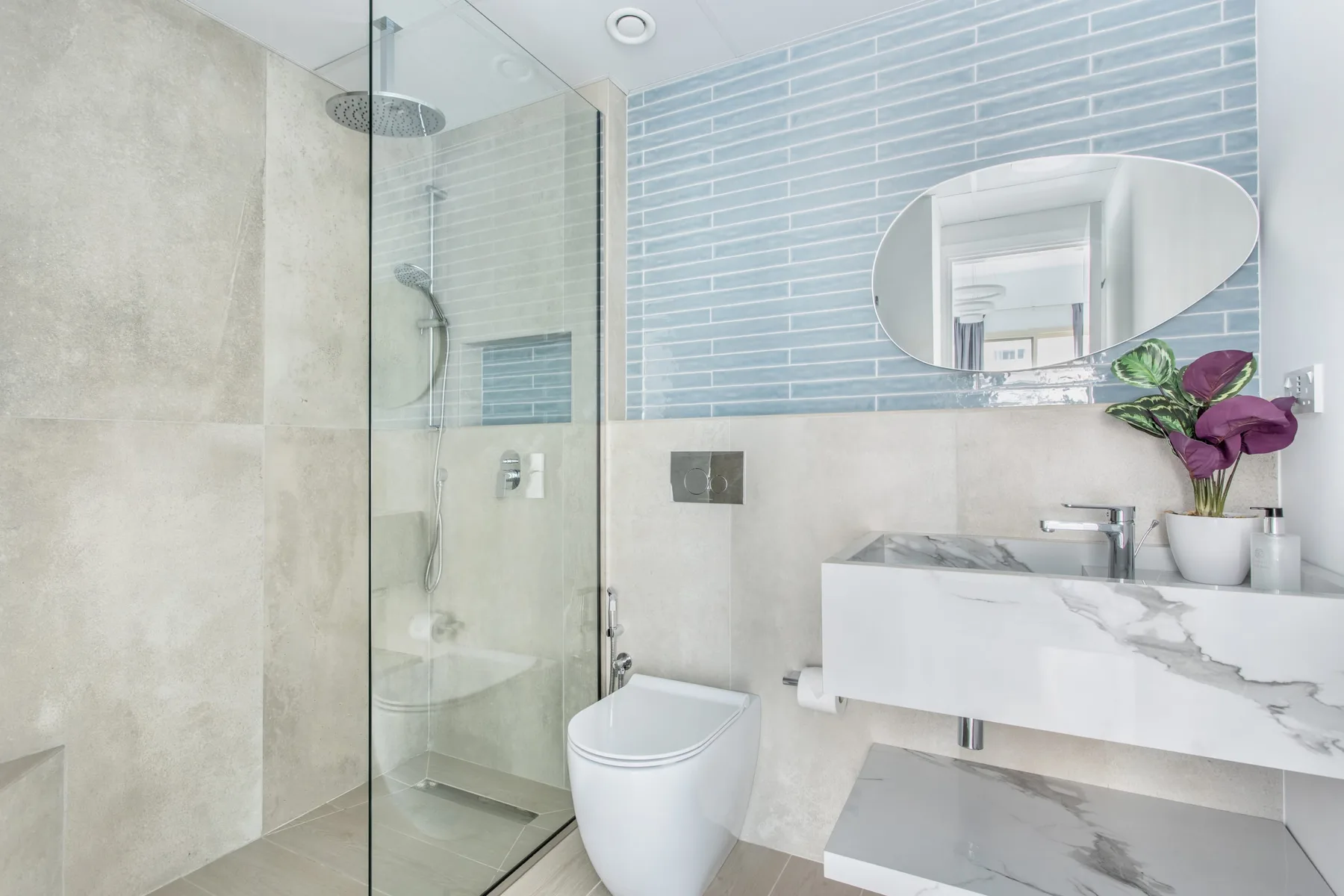 Un baño moderno con ducha de vidrio, inodoro y lavabo flotante.