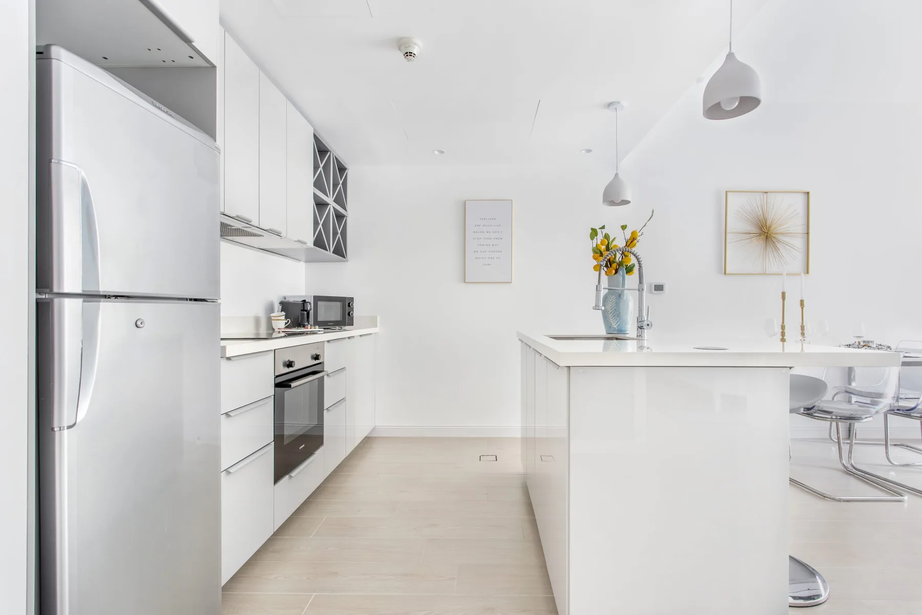 Una cocina moderna y luminosa con gabinetes blancos, electrodomésticos de acero inoxidable e isla central.