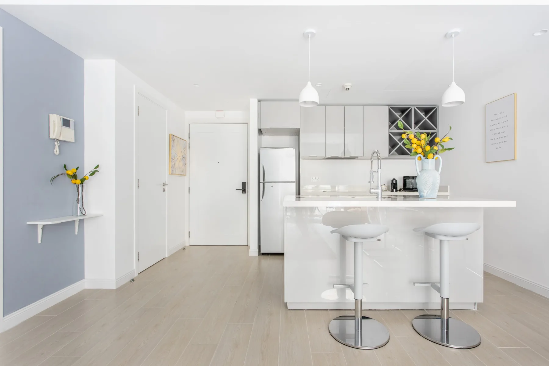 Una cocina luminosa con una isla blanca, asientos de barra y flores sobre la encimera.