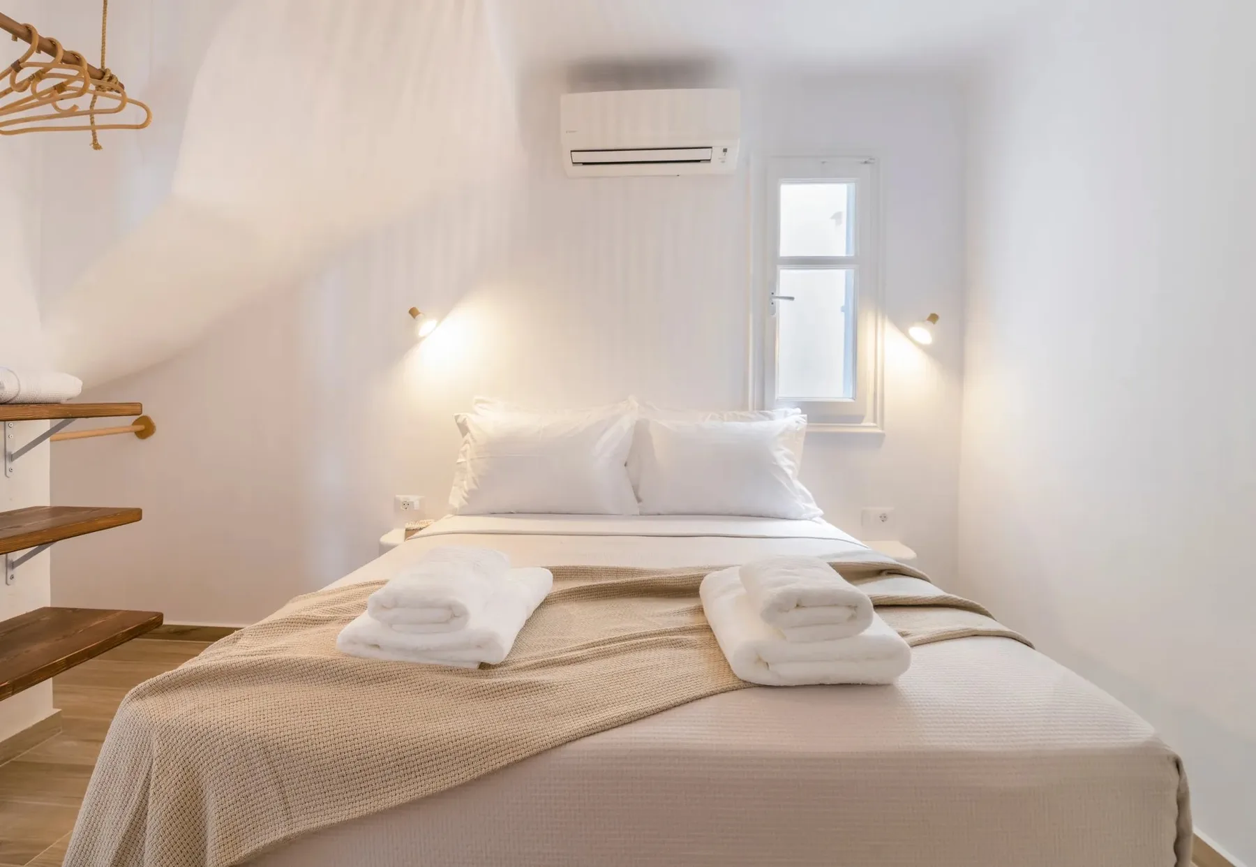 A bright bedroom with a neatly made bed and folded towels.