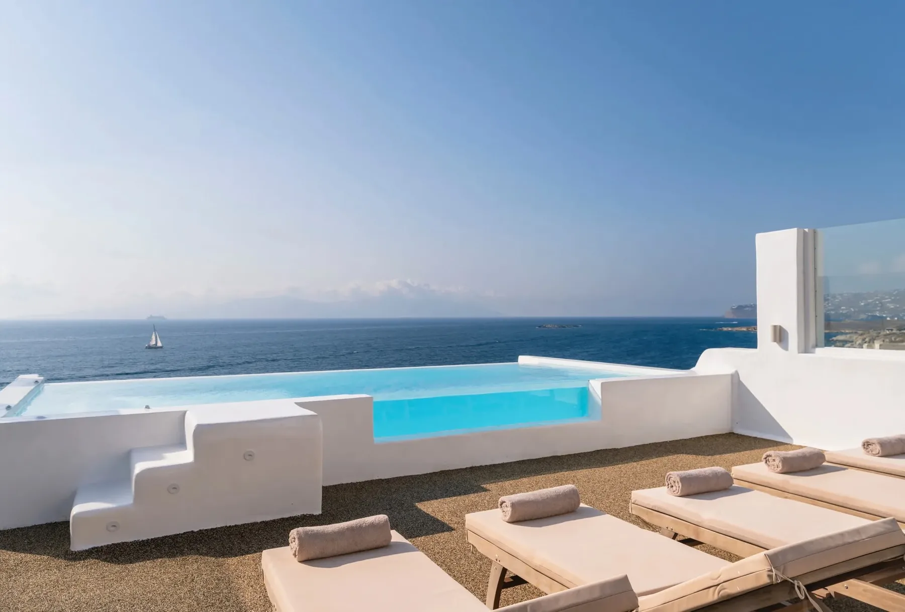 Una piscina en la azotea da al mar, con tumbonas dispuestas junto a la terraza.