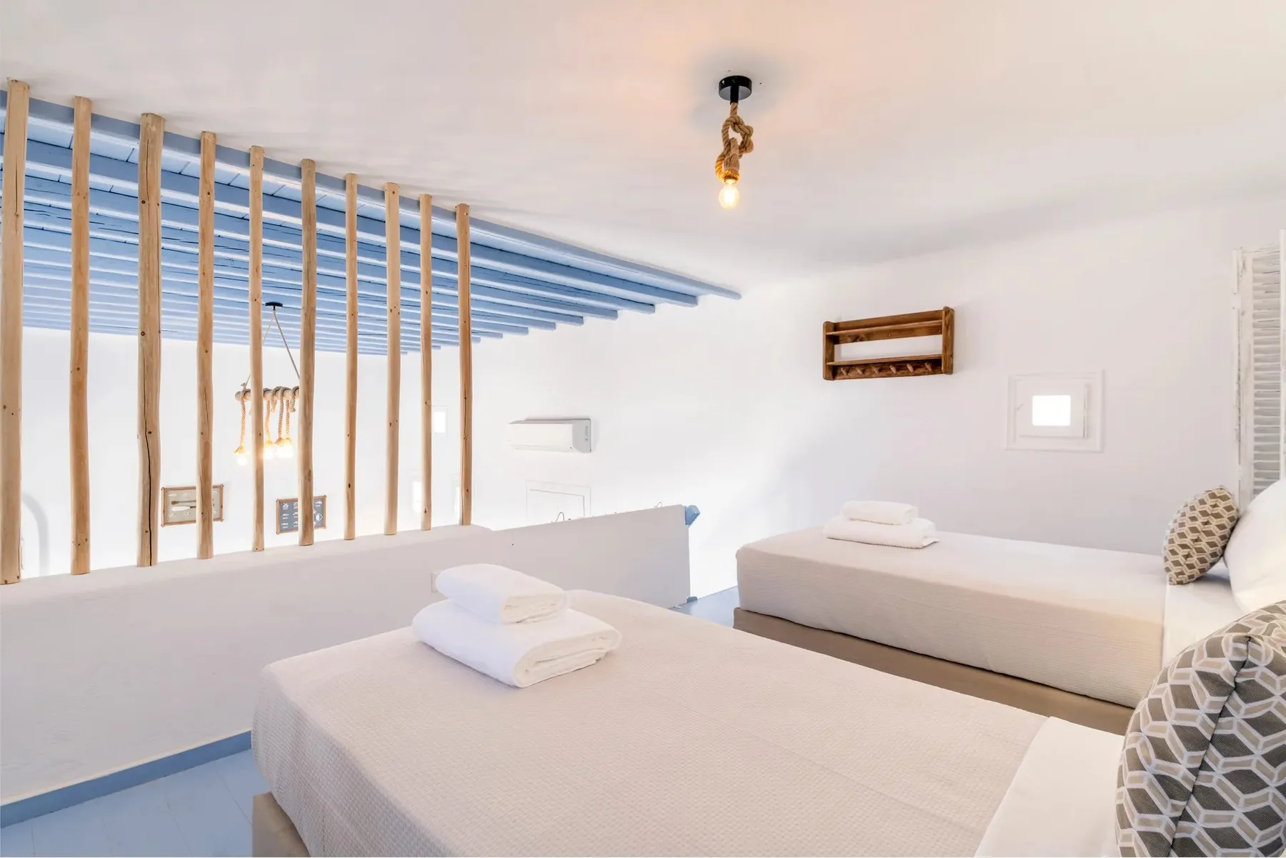A bright bedroom with two beds and white linens.