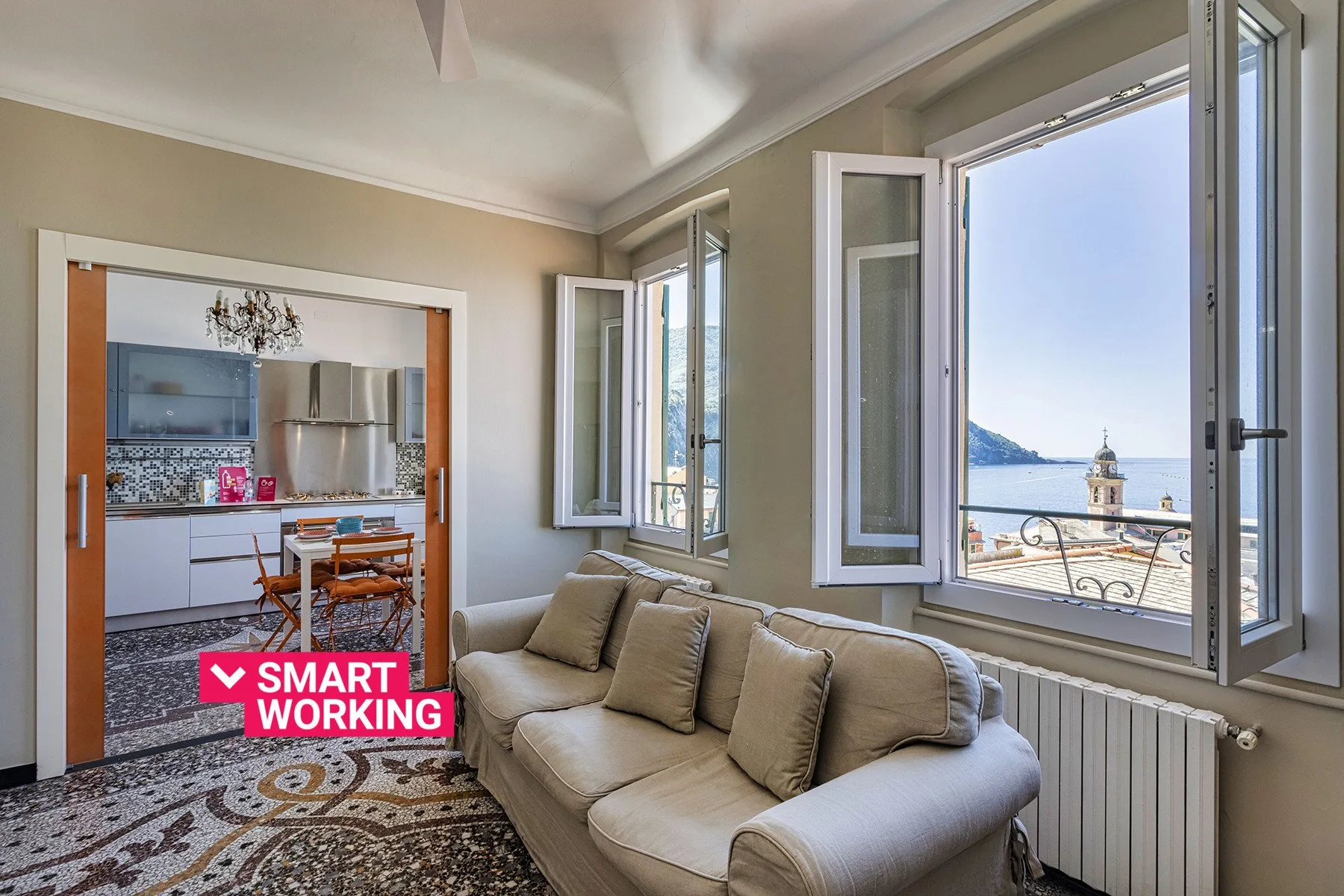 A living room with seating beside open windows overlooking the water.