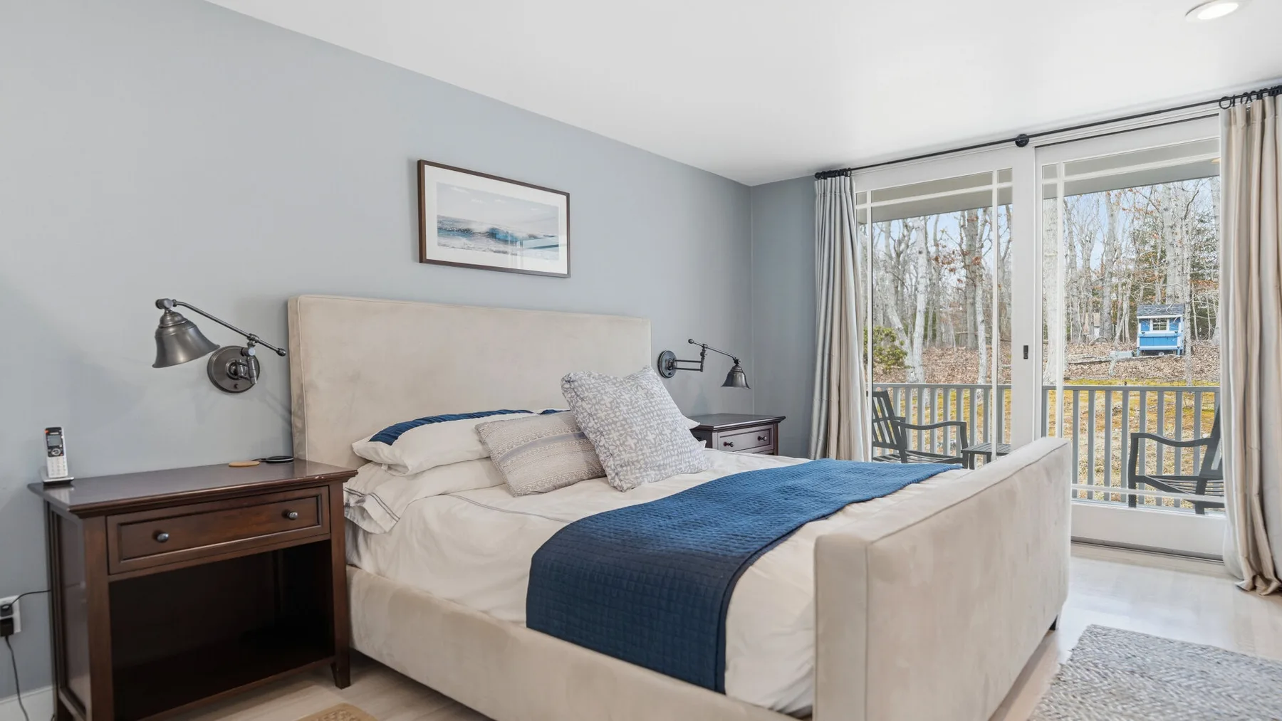 Un dormitorio con una cama, mesitas de noche y puertas de vidrio que dan a un balcón.
