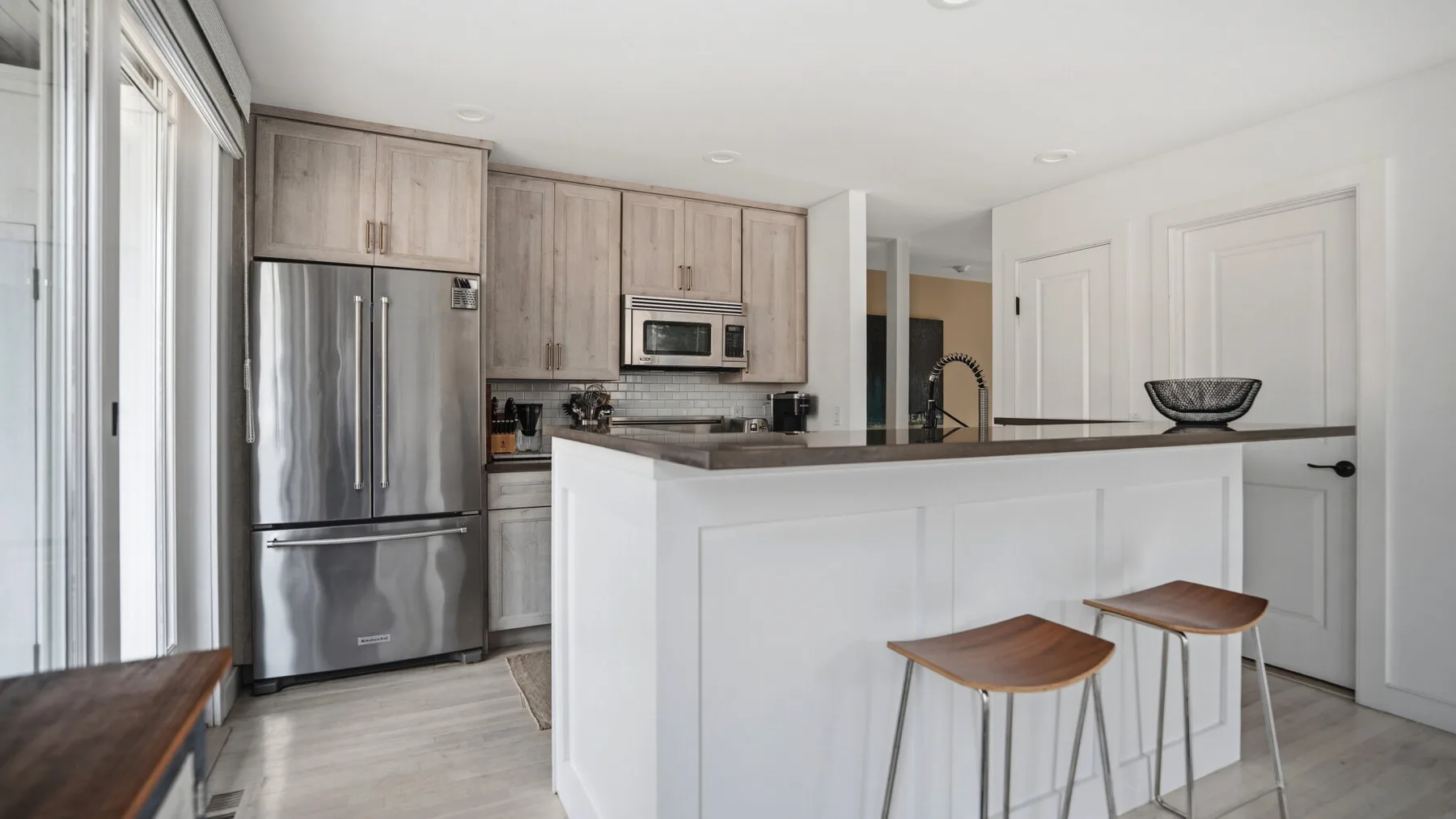 Una cocina luminosa con una isla grande, asientos de barra y electrodomésticos de acero inoxidable.