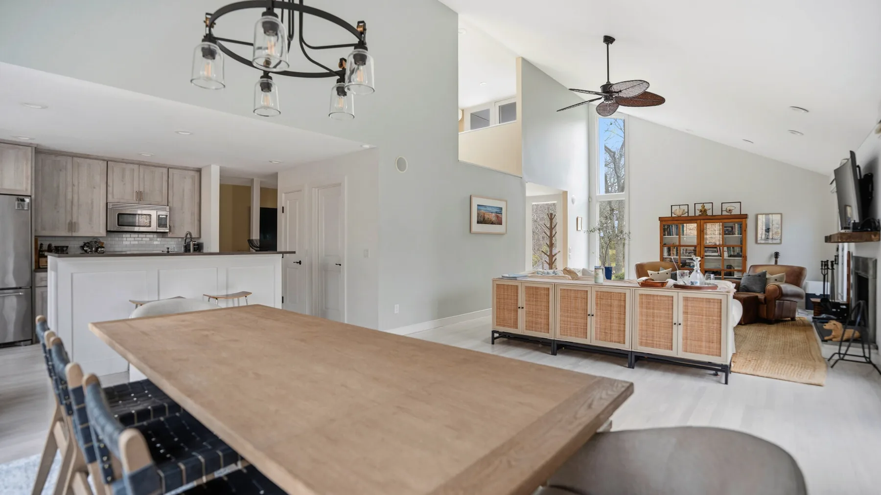 Un espacio abierto de sala y comedor con una mesa larga de madera y cocina.