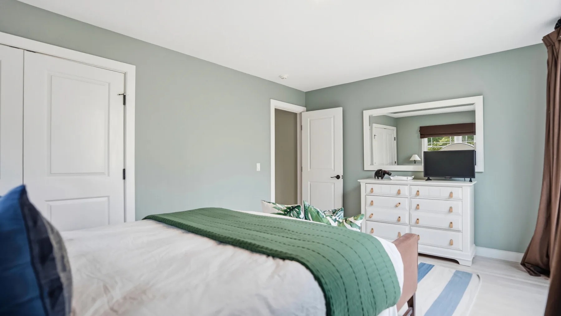 Un dormitorio con una cama vestida con ropa de cama blanca y verde.