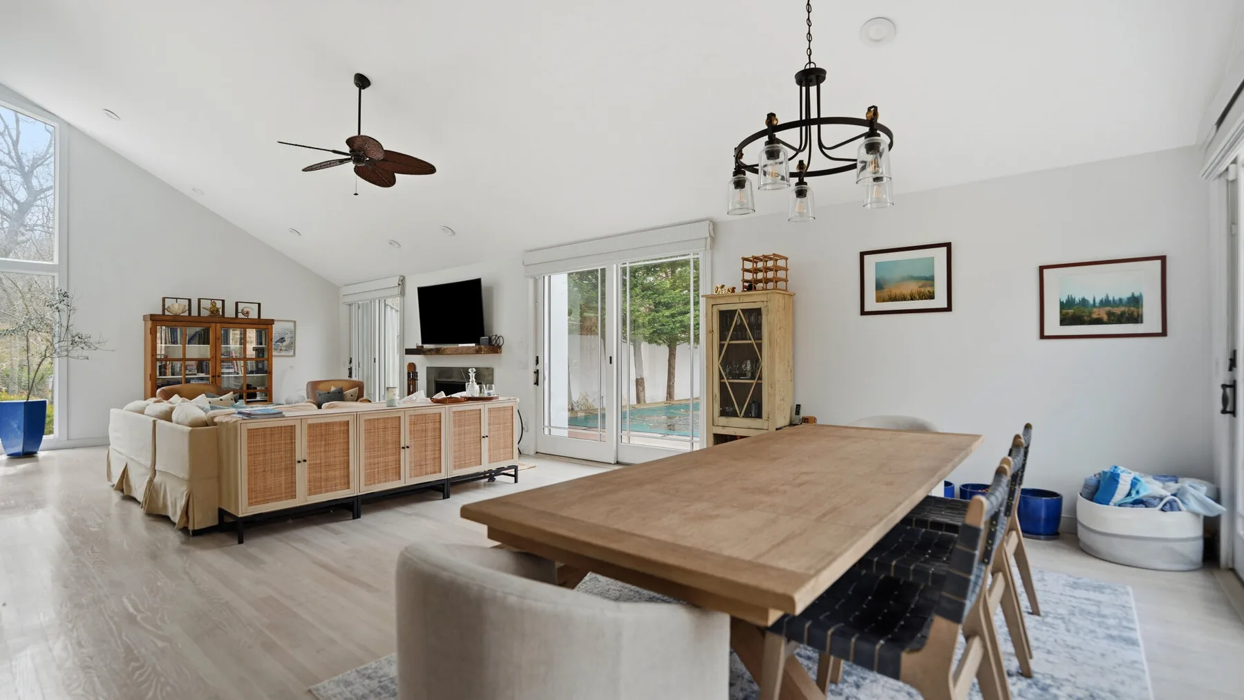 Un luminoso comedor y sala de estar con una mesa larga de madera y grandes ventanas.