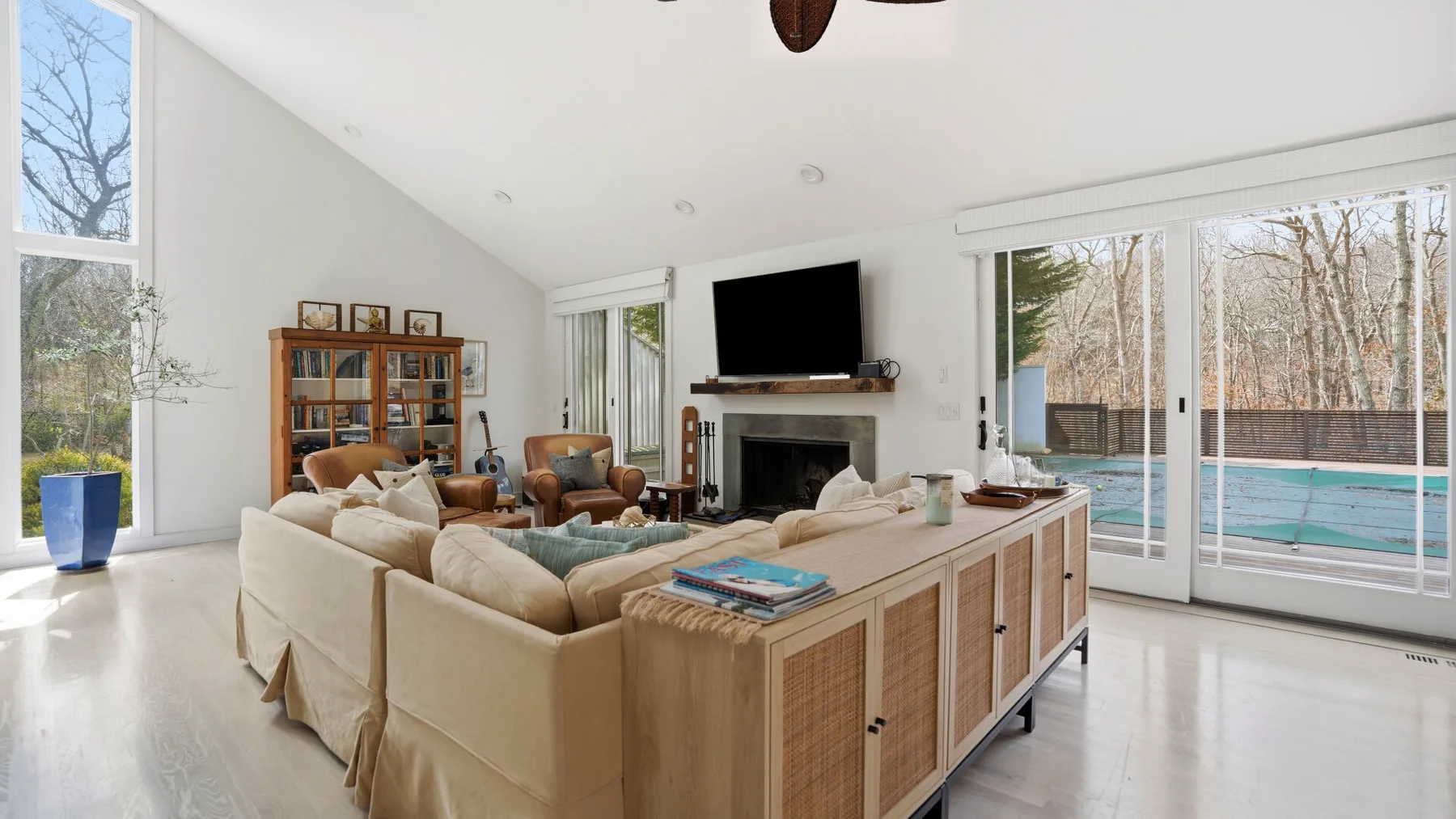 Una sala luminosa con asientos, un televisor y ventanas amplias.