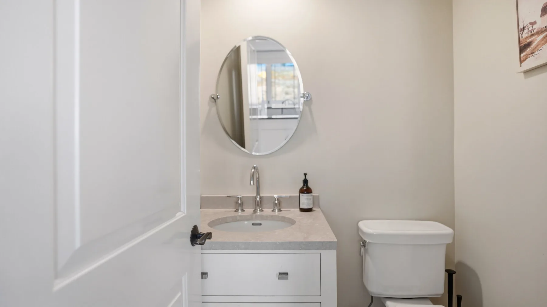 Un baño con lavabo, espejo ovalado e inodoro.