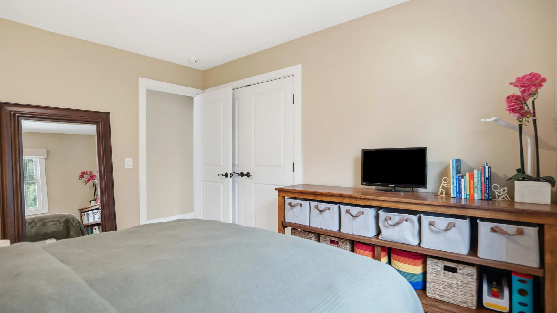 Un dormitorio con una cama y una cómoda larga con un televisor encima.