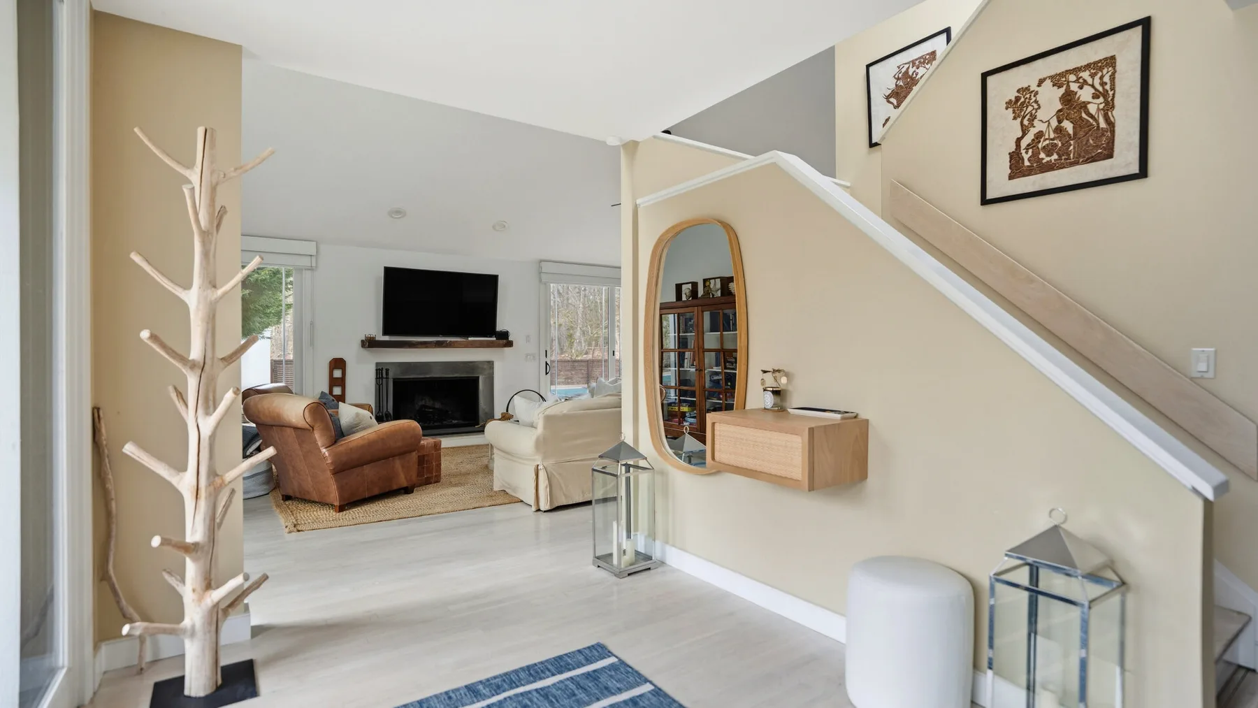 Una sala luminosa con asientos, un televisor y una escalera junto a la pared.