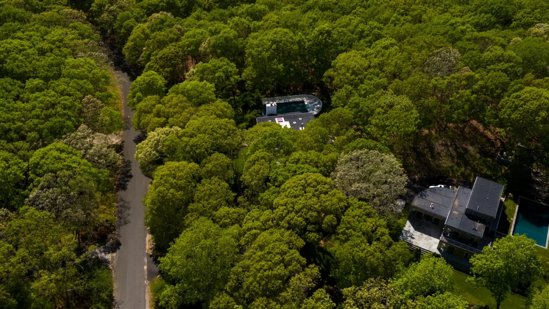 Vista aérea de edificios y una piscina entre árboles frondosos.