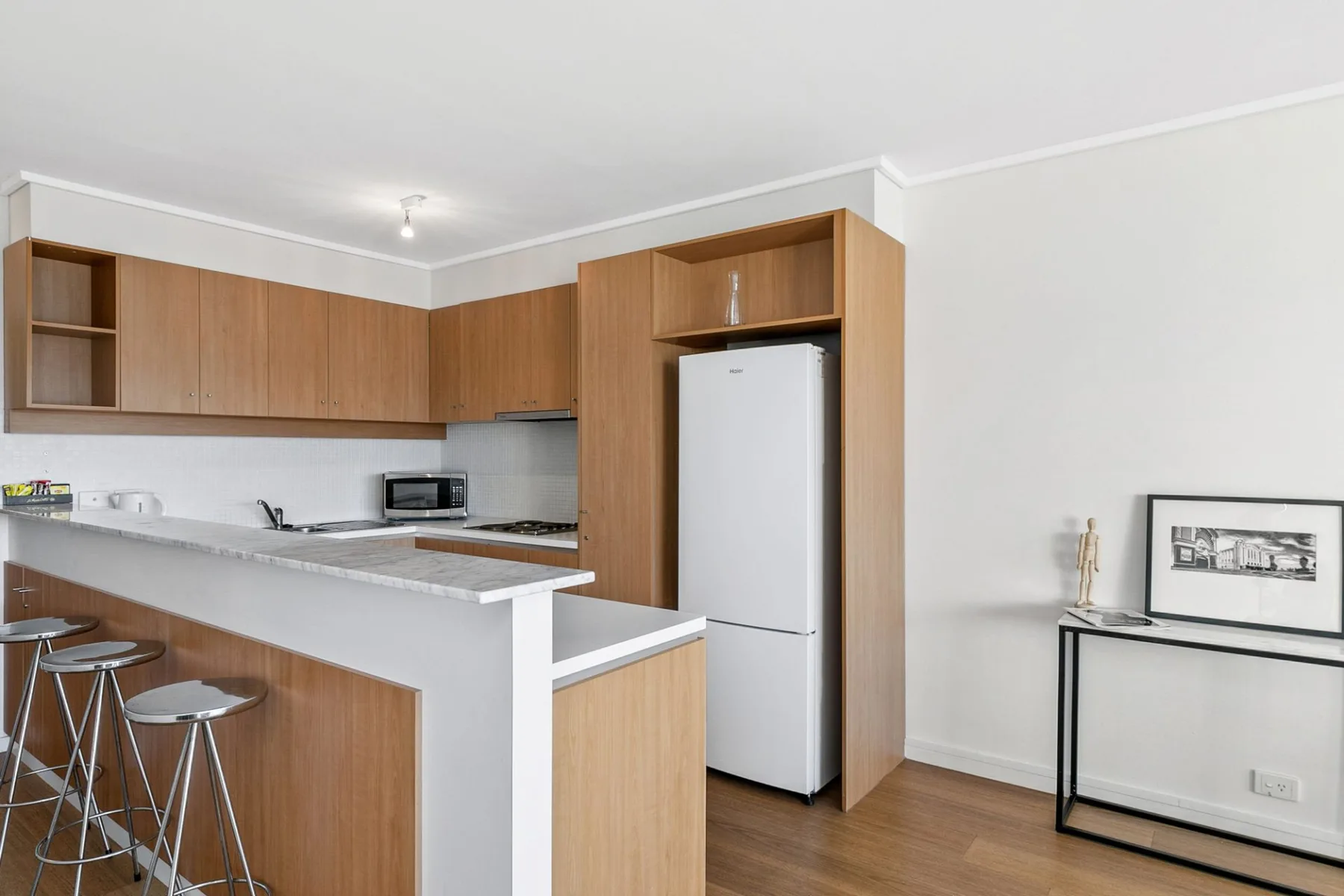 Una cocina compacta con gabinetes de madera, una barra y un refrigerador.
