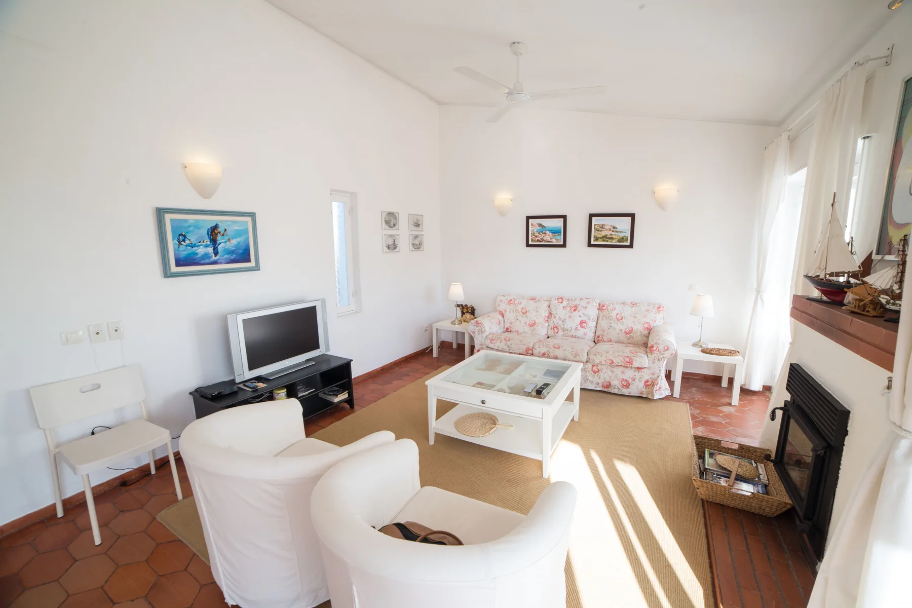 Una sala luminosa con asientos alrededor de una mesa de centro y un televisor.