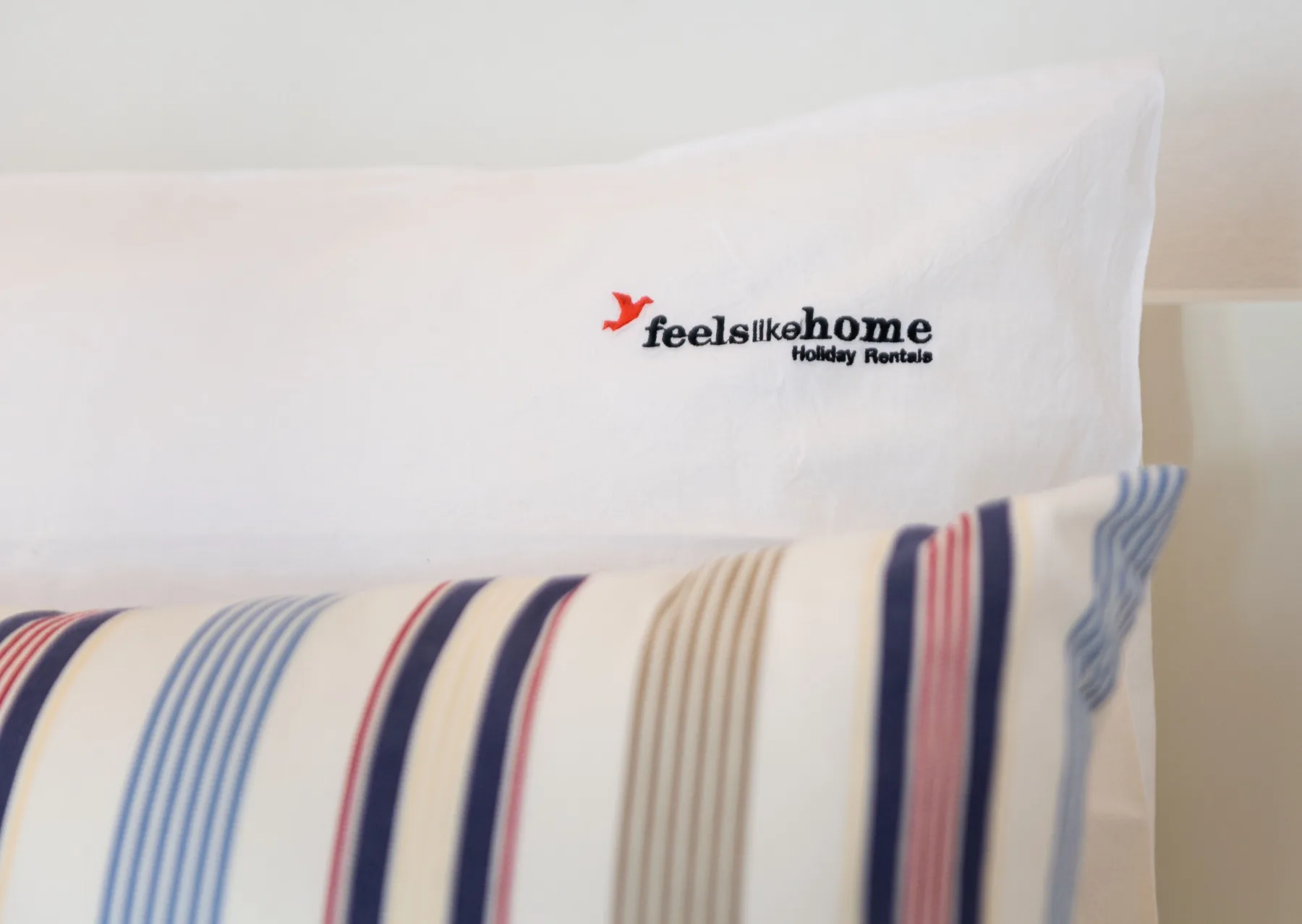 Una cama con una almohada blanca y ropa de cama a rayas.