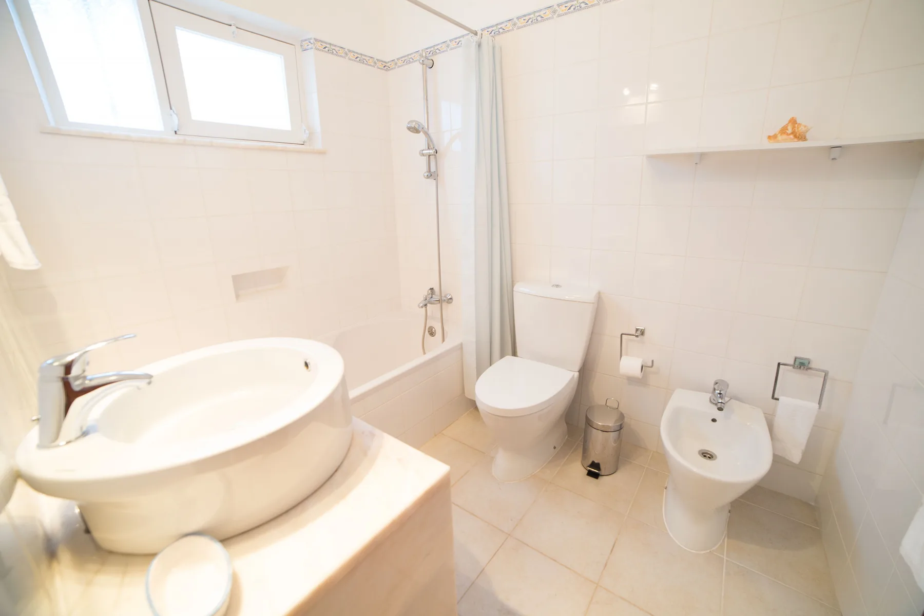 Un baño alicatado con bañera, inodoro y bidé.