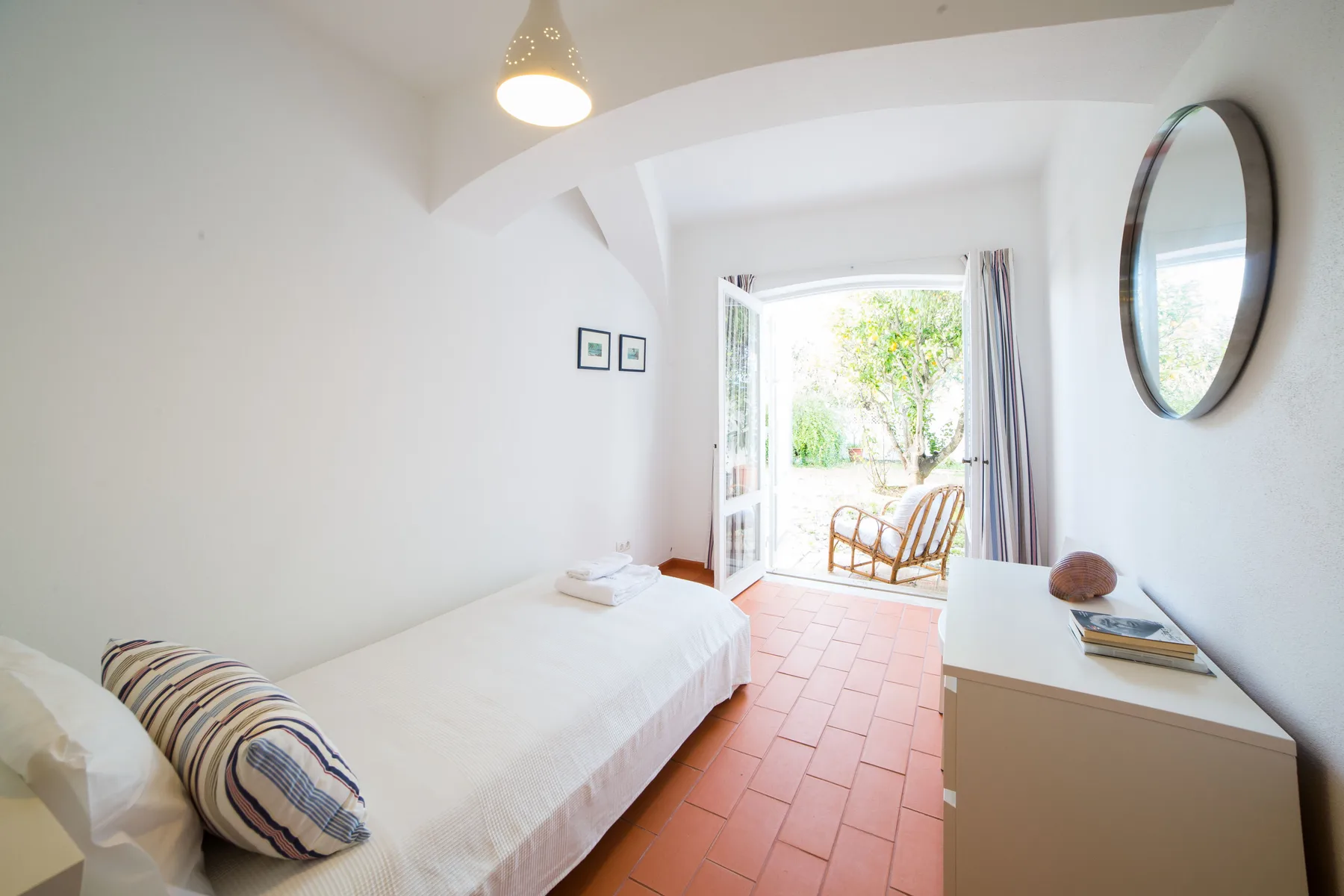Un dormitorio luminoso con una cama y puertas abiertas que dan a un patio.