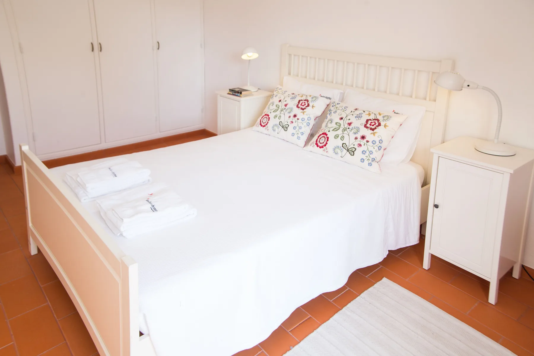 Un dormitorio con una cama bien hecha y mesitas de noche.