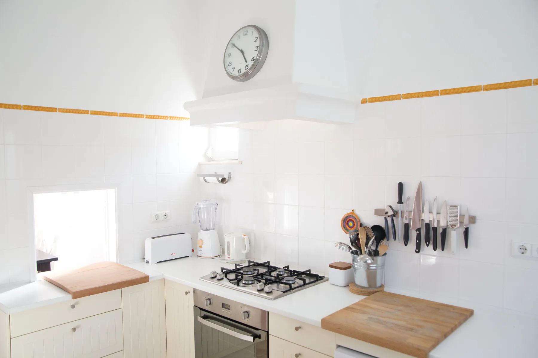 Una cocina luminosa con fogones, encimera y utensilios en la pared.