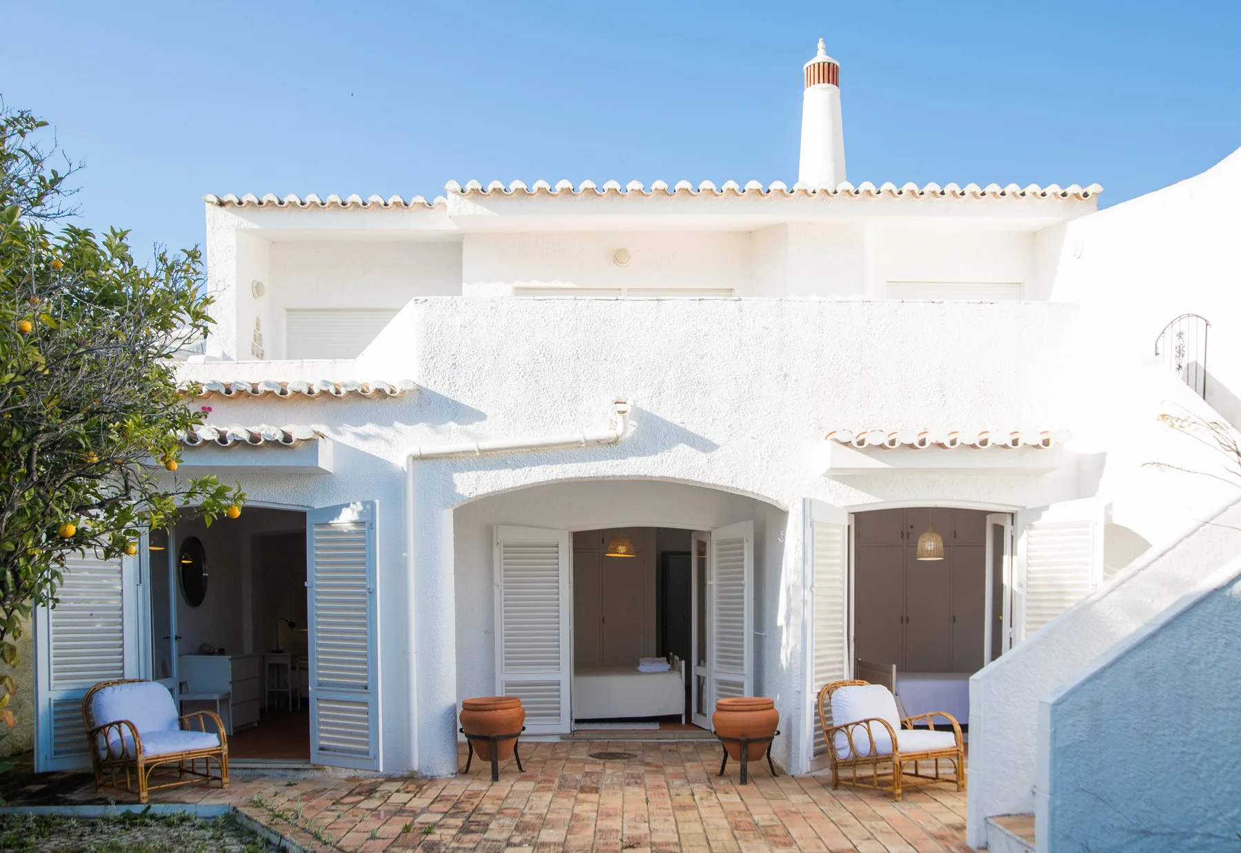 Exterior de una casa blanca con puertas abiertas y un patio pavimentado.