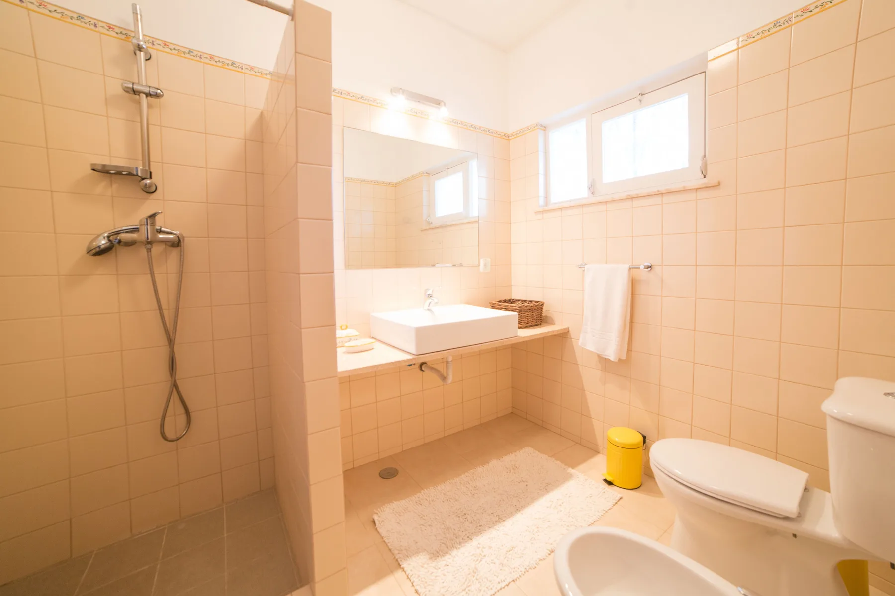 Un baño alicatado con ducha, lavabo e inodoro.