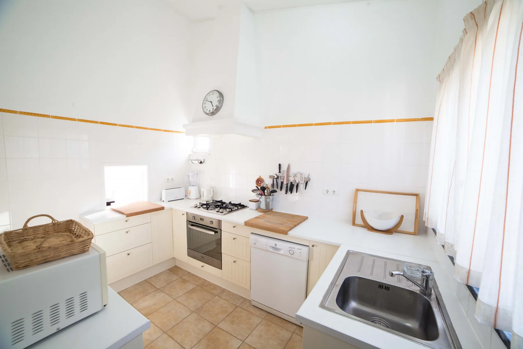 Una cocina luminosa con gabinetes claros, una placa de cocción y un fregadero.
