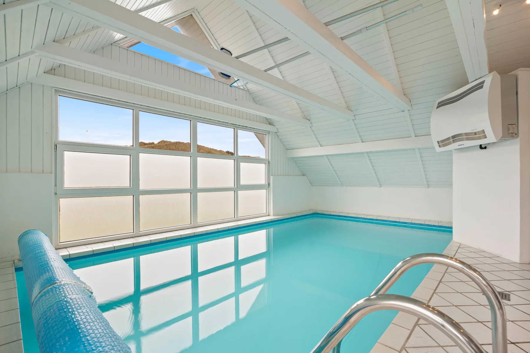 Piscina cubierta con grandes ventanas y un techo alto e inclinado.
