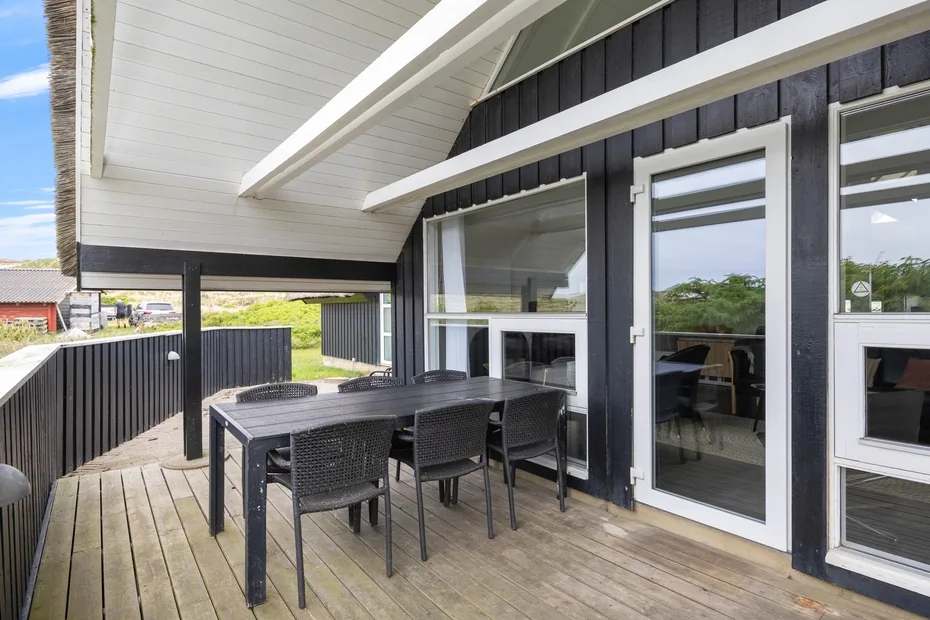 Una terraza exterior cubierta con una mesa de comedor junto a grandes puertas de vidrio.