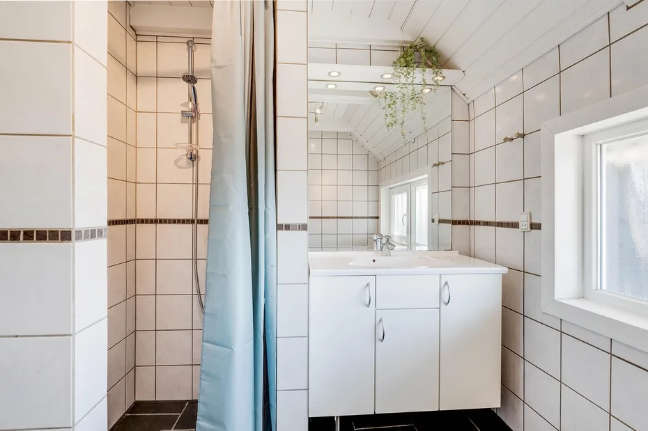 Un baño alicatado con ducha, lavabo, espejo y ventana.