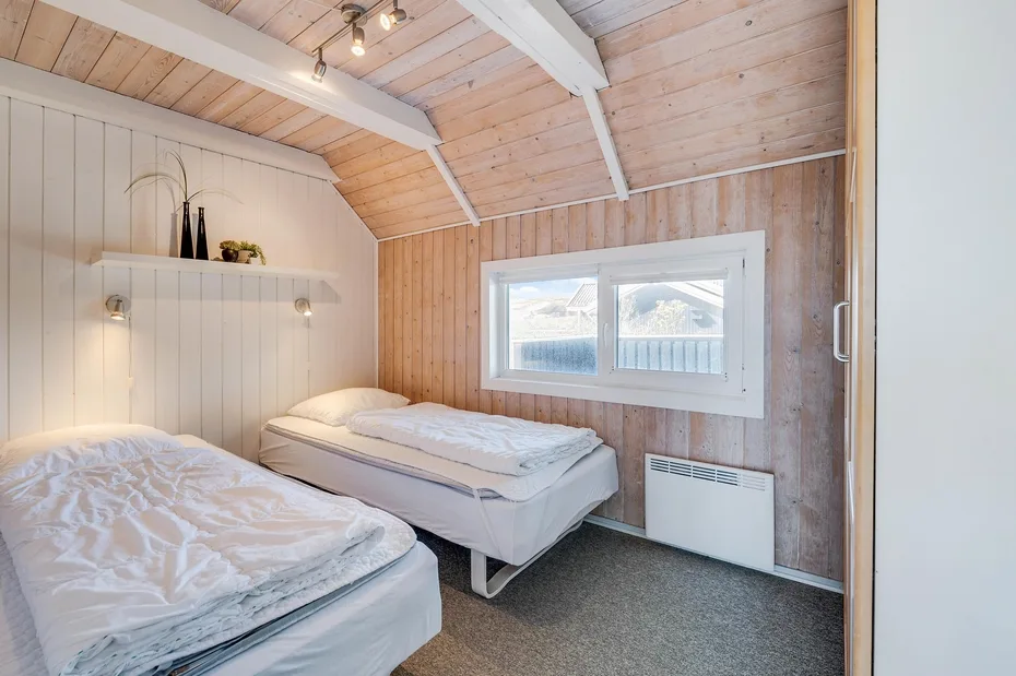 Un dormitorio revestido de madera con dos camas y una ventana.