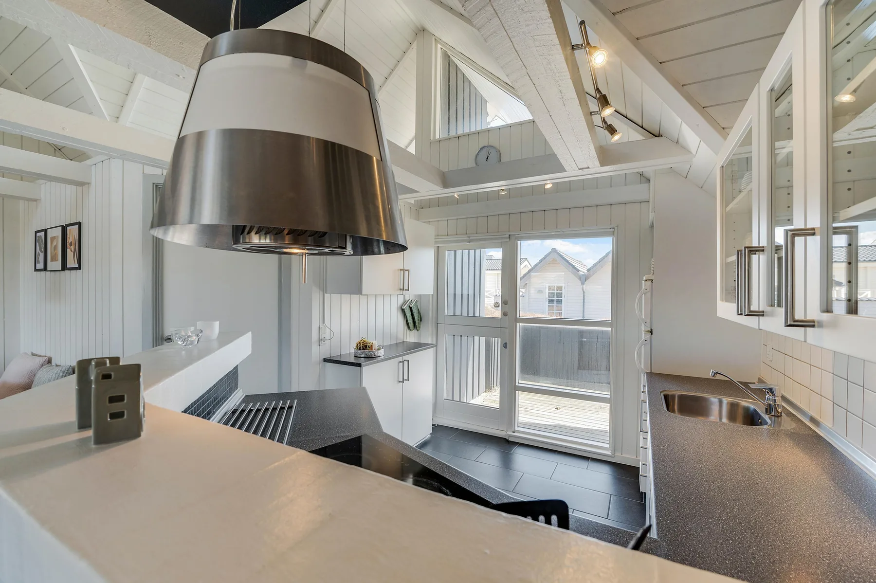 Una cocina luminosa con una zona de cocción central y puertas de vidrio al exterior.
