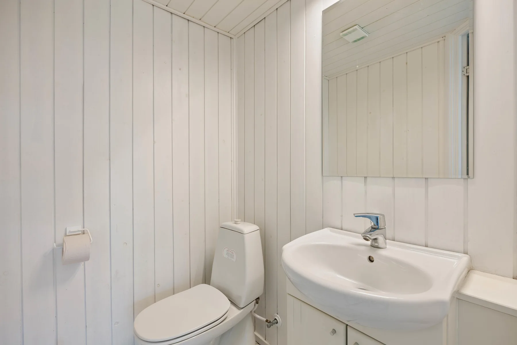 Un baño con un inodoro y un lavabo debajo de un espejo.