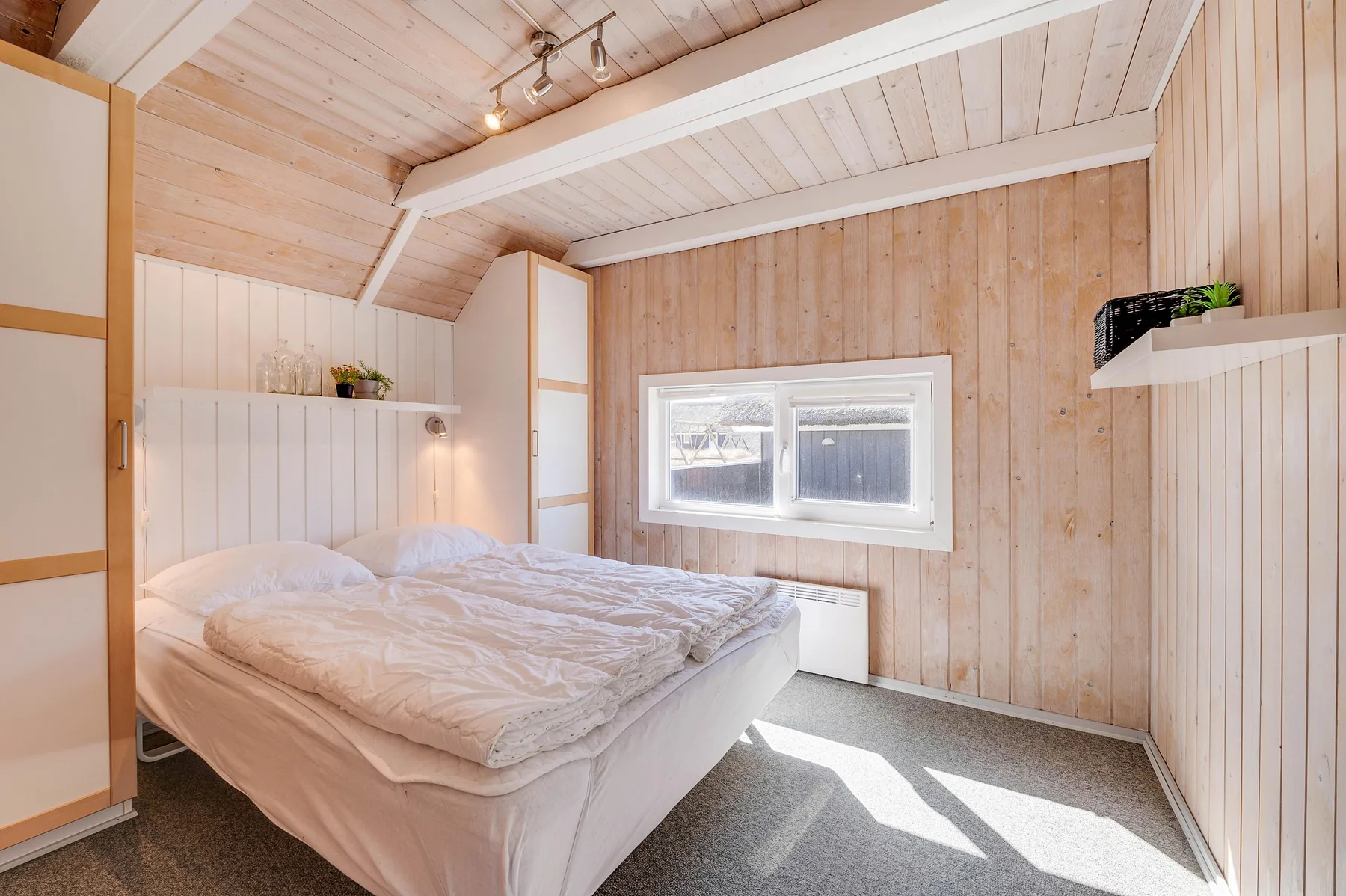 Dormitorio con una cama doble bajo un techo de madera inclinado.
