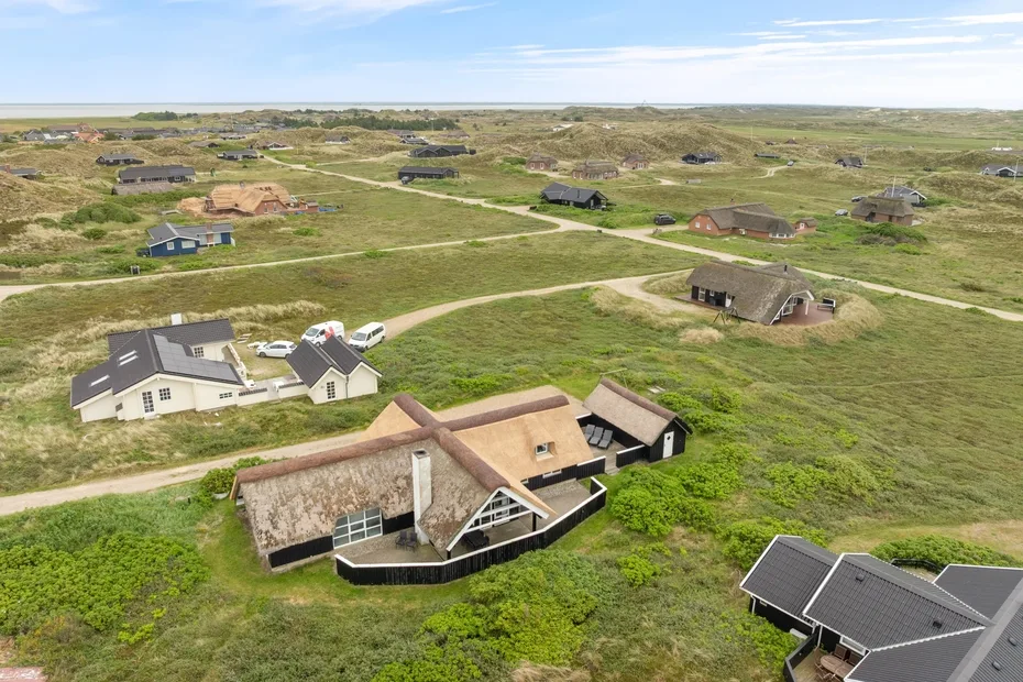 Vista aérea de casas dispersas entre dunas cubiertas de hierba y caminos sinuosos.