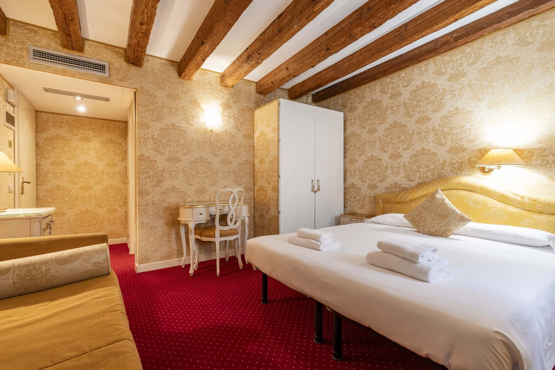 A bedroom with two beds, a wardrobe, and exposed wooden ceiling beams.