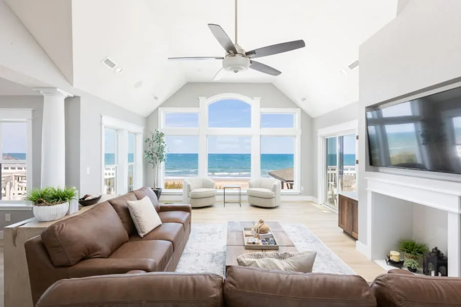 A bright living room with seating facing large windows overlooking the ocean.