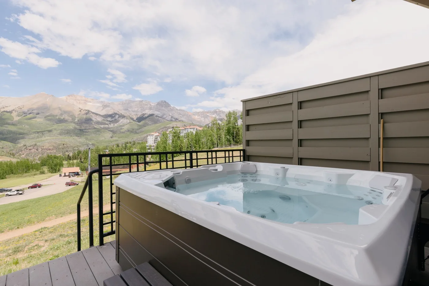 A hot tub sits on an outdoor deck overlooking a mountain landscape.