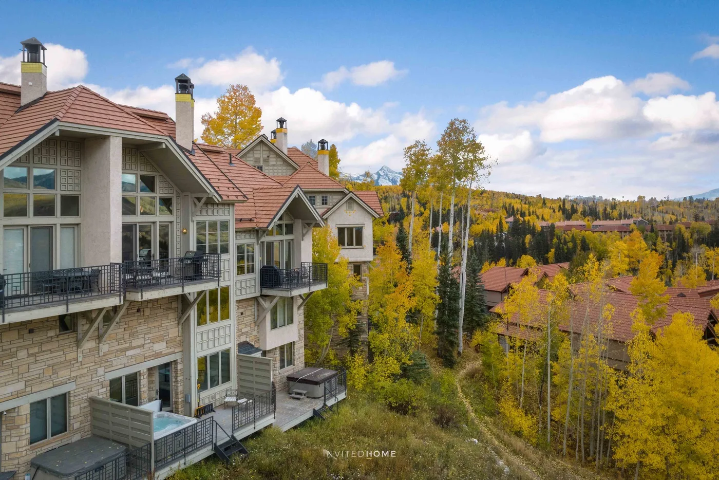 A row of mountain residences overlooks an autumn landscape beneath a blue sky.